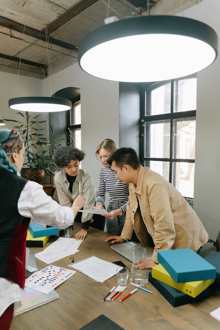 ours-journey Diverse team of young professionals brainstorming together in a contemporary office setting.