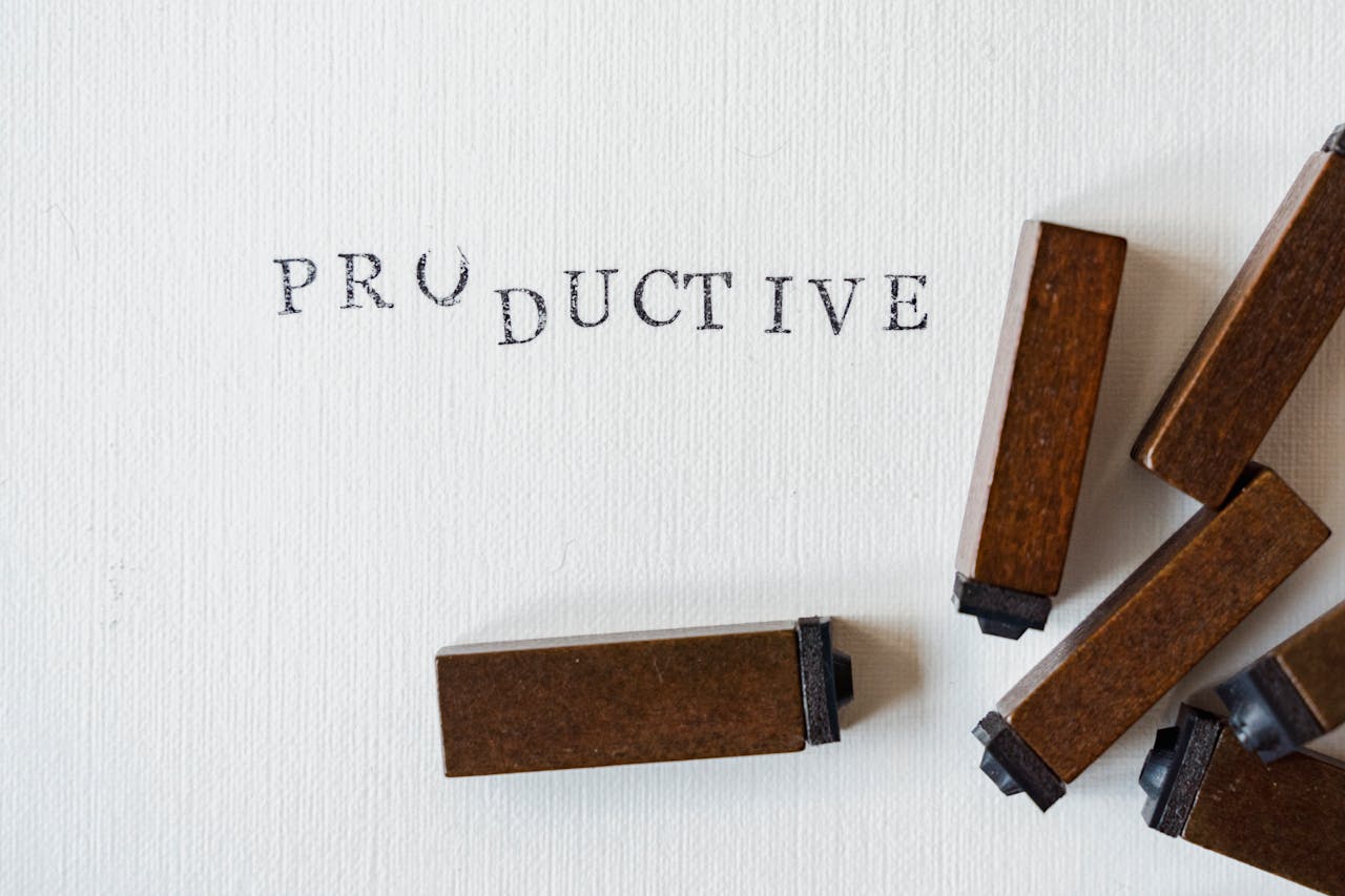 services-02 Wooden letter stamps forming the word 'productive' on a white canvas surface.